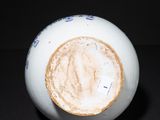a white and blue vase on a black surface