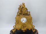 a gold clock sitting on top of a black marble base