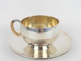 une tasse et une soucoupe en argent posées sur une soucoupe