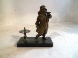 une statue en bronze représentant un homme coiffé d'un chapeau et tenant une pipe