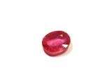 a close up of a red ruby stone on a white surface