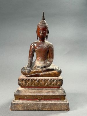 statue of a seated buddha sitting on a stone block
