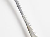 a silver spoon with a fork on it on a white surface