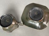 a silver plate with a clock on it next to a silver plate with a clock on it