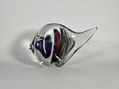 un gros plan d'une sculpture de poisson en verre posée sur une surface blanche
