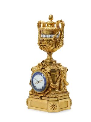 a gold clock on a pedestal with a crown on top