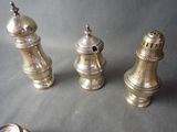 three silver salt and pepper shakers on a table