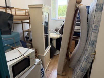 an image of a messy room with a microwave and a bed