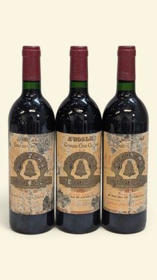 trois bouteilles de vin rouge posées l'une à côté de l'autre sur une surface blanche