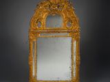 an ornately carved mirror with a gold frame on a grey background