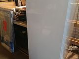 a white refrigerator sitting in a warehouse next to other items