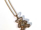 un collier en or orné d'un ours, posé sur un fond blanc