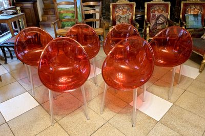 four red plastic chairs sitting on top of a tiled floor