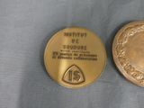 two gold medals are sitting next to each other on a blue cloth