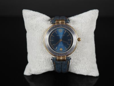 une photo d'une montre bleue posée sur un oreiller blanc
