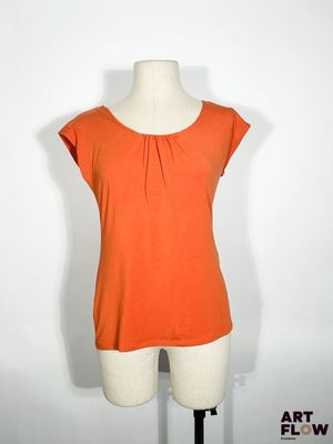 un haut orange posé sur un présentoir à mannequin, sur fond blanc
