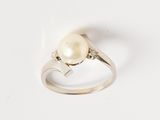 une image d'une bague en perles et diamants sur une surface blanche