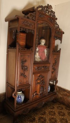 a china cabinet with a doll on top of it