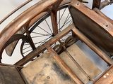 a small antique car with a wooden seat and a wheel