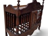 a small wooden crib with a carved headboard