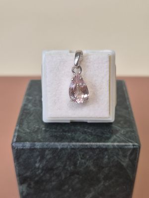 a close up of a pink diamond pendant on a white box
