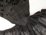 an old black dress with black lace on it laying on a white surface