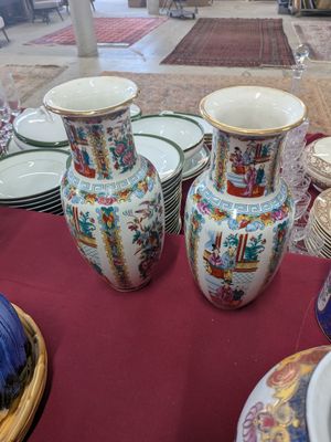 many vases and plates on a table with a red table cloth