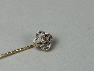 a silver and gold pin with a flower on it