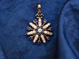 a close up of a gold and diamond pendant on a blue cloth