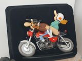 a figurine of a man riding a motorcycle with a dog on the back