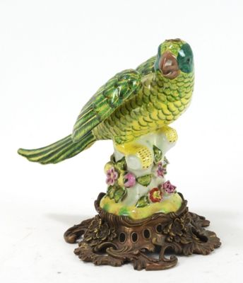 une figurine représentant un perroquet vert posé sur une souche d'arbre