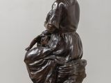 bronze statue of a woman sitting on a stool with a child