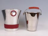 two silver buckets with red handles sitting next to each other on a white surface
