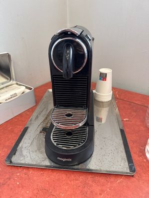 a black coffee machine sitting on a counter next to a cup