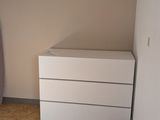 a white chest of drawers in the corner of a room