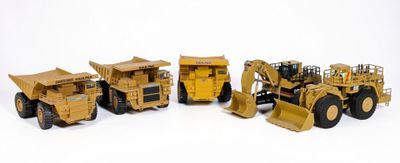 quatre engins de chantier miniatures posés les uns à côté des autres