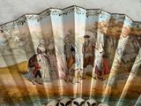 a fan with a painting of people on it