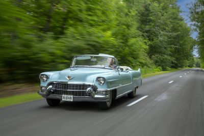 a car that is driving down the road with trees in the background