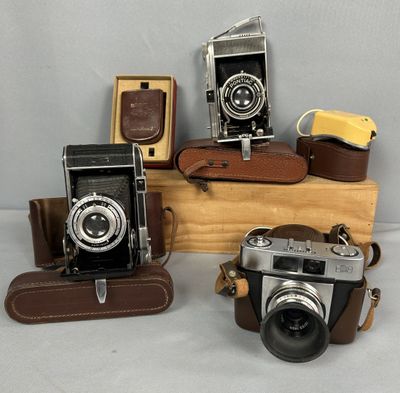 trois vieux appareils photo posés sur une caisse en bois