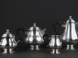 a group of silver tea and coffee pots sitting on a table