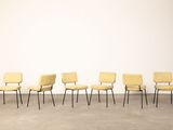six chaises jaunes alignées contre un mur blanc