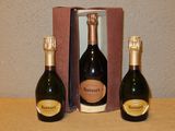 trois bouteilles de champagne posées sur une table à côté d'un carton de vin