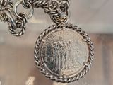 a necklace with a coin on it hanging from a chain