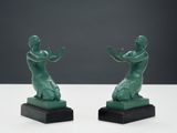 two green statues of a woman and a man on a white surface