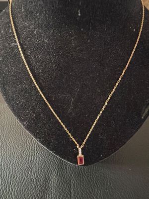 un collier en or orné d'une pierre rouge sur un mannequin noir