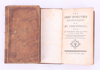 un livre ouvert, à la couverture marron, posé sur une surface blanche