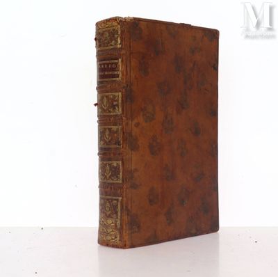 un vieux livre marron aux tranches dorées posé sur une surface blanche
