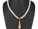 un collier de perles blanches orné d'un pendentif plaqué or sur un mannequin