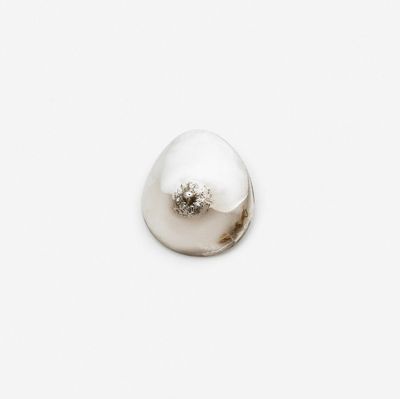 a white pearl on a white surface with a silver object in the middle