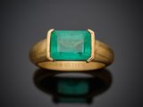 gros plan d'une bague en or avec une pierre en émeraude